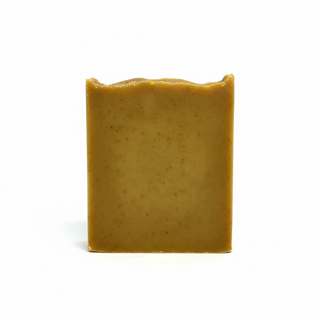 A single rectangular bar of handmade soap in a warm golden-brown color, standing upright against a white fabric backdrop.