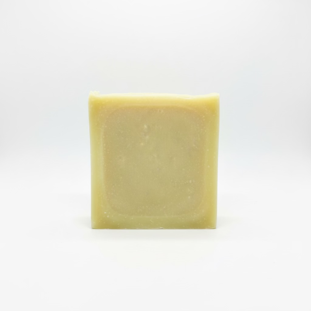 A single rectangular bar of pale yellow soap with rounded corners, standing upright against a light gray fabric background.