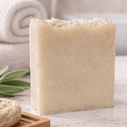 Bar of soap and its packaging on a bathroom counter with plants in the background