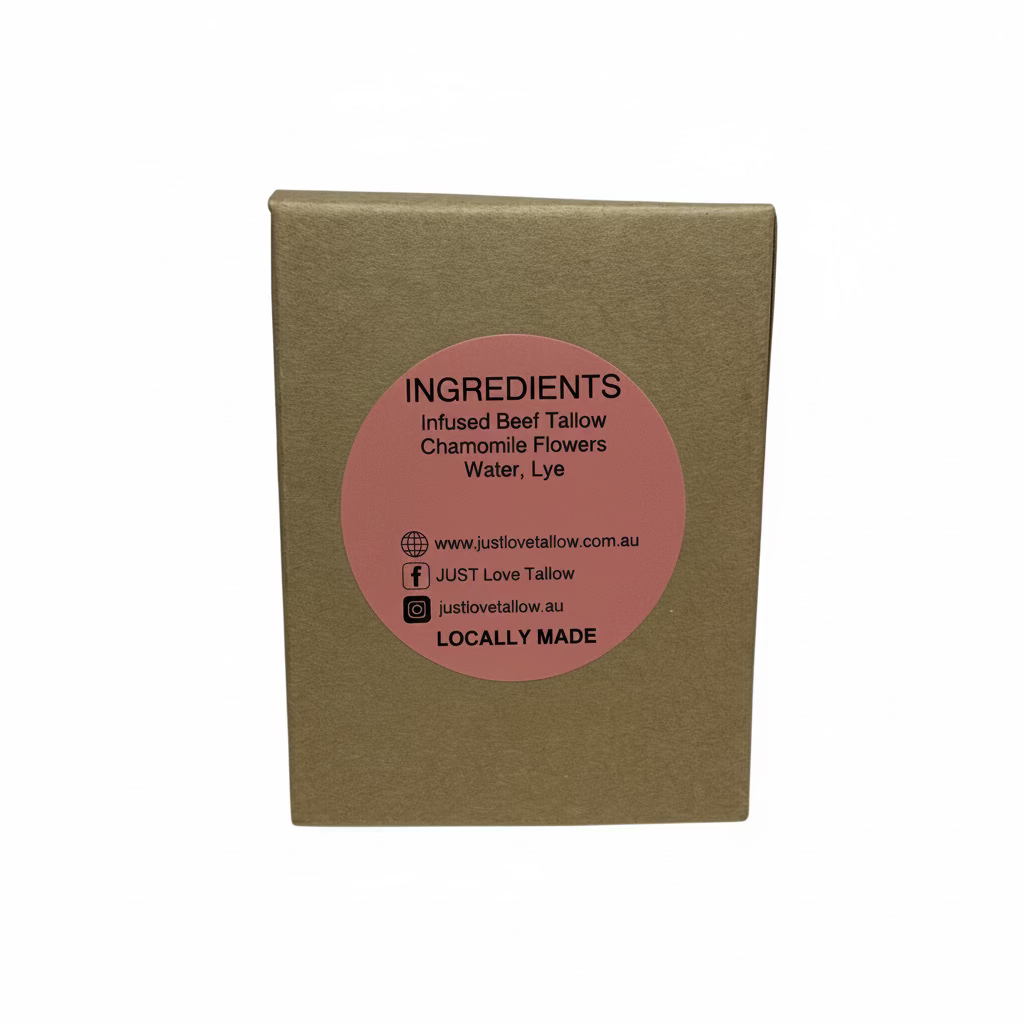 A square brown kraft paper box standing upright against a light gray fabric backdrop, featuring a circular pink label on the front with black text listing ingredients and the brand JUST Love Tallow.